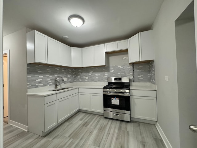 kitchen featuring light wood-type flooring, stainless steel stove, sink, decorative backsplash, and white cabinets