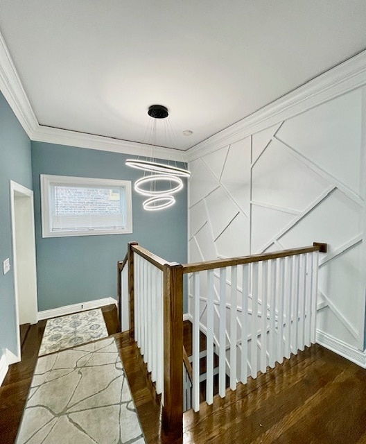 stairway featuring ornamental molding, wood-type flooring, and an inviting chandelier