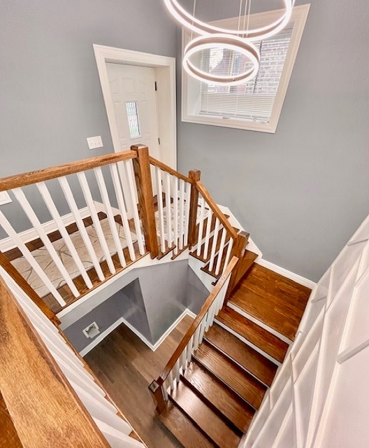 stairway featuring wood-type flooring and a notable chandelier