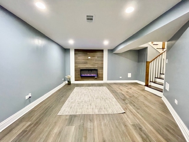 basement with wood-type flooring and a large fireplace