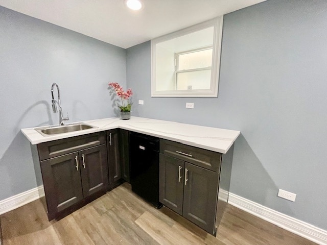 interior space with kitchen peninsula, dishwasher, light wood-type flooring, dark brown cabinetry, and sink