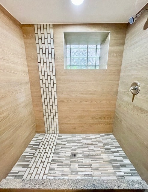 bathroom featuring walk in shower and wood walls