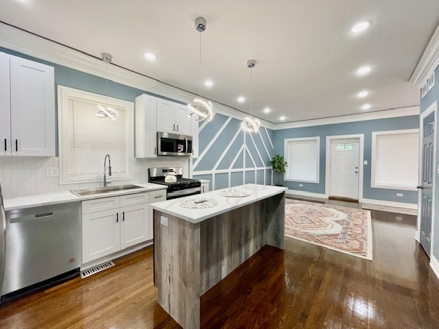 kitchen featuring pendant lighting, stainless steel appliances, white cabinetry, and sink