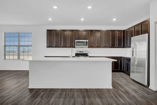 kitchen featuring stainless steel appliances, a center island with sink, and hardwood / wood-style flooring