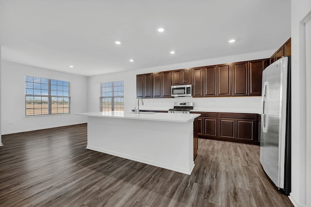 kitchen with an island with sink, appliances with stainless steel finishes, dark hardwood / wood-style floors, and sink