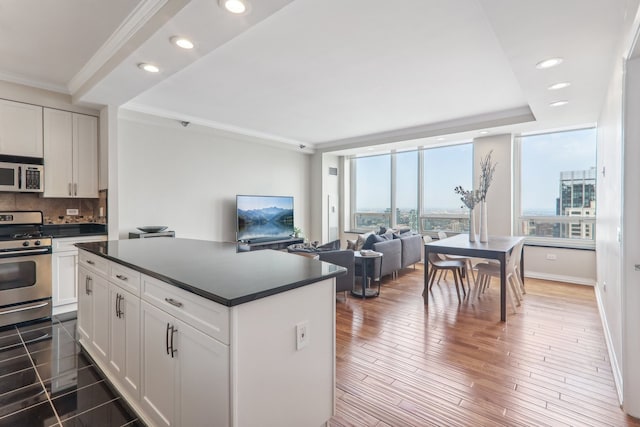 kitchen featuring tasteful backsplash, white cabinets, dark hardwood / wood-style flooring, stainless steel appliances, and crown molding