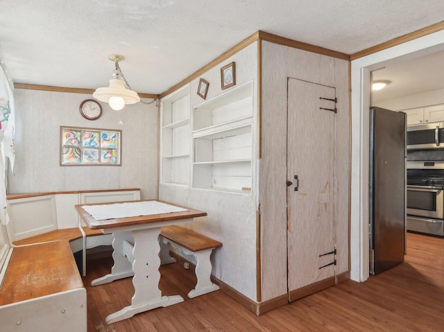 dining area featuring built in shelves, light wood-type flooring, and crown molding