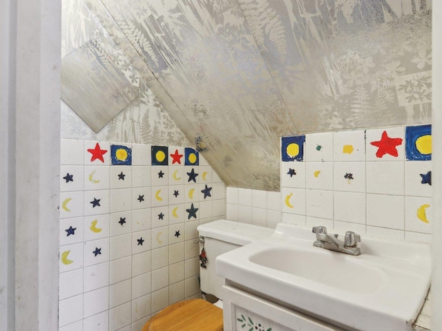 bathroom with vanity, toilet, and tile walls