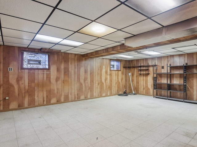 basement with a drop ceiling and wood walls