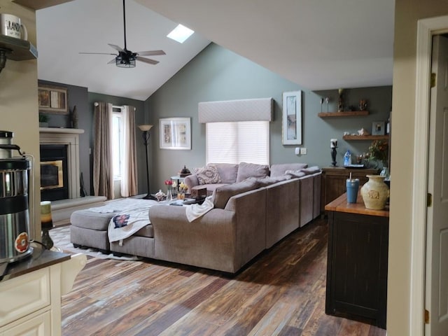 living room with ceiling fan, lofted ceiling with skylight, and dark wood-type flooring