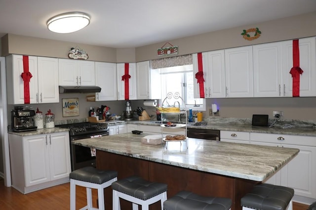 kitchen with black appliances, a kitchen island, a kitchen bar, and white cabinetry