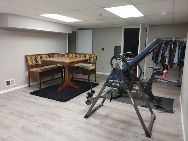 workout room with a drop ceiling and light hardwood / wood-style floors