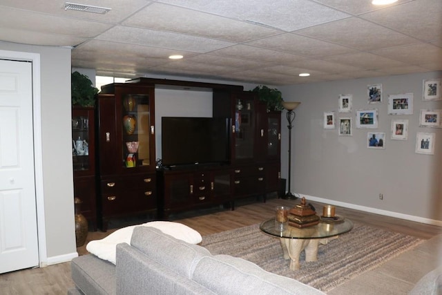 living room featuring light wood-type flooring and a drop ceiling