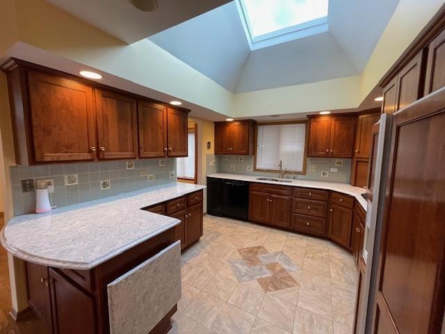 kitchen featuring high vaulted ceiling, sink, a skylight, decorative backsplash, and light tile patterned floors