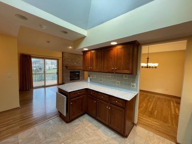 kitchen with backsplash, decorative light fixtures, vaulted ceiling, light hardwood / wood-style flooring, and a notable chandelier