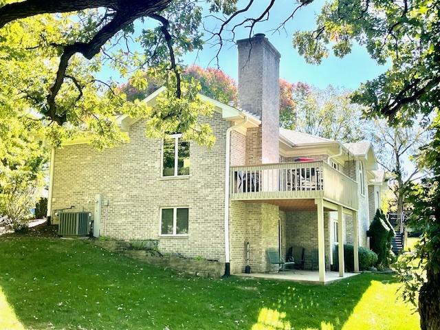 rear view of property featuring a lawn, a patio, and central AC unit