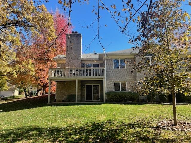 back of property featuring a wooden deck and a yard