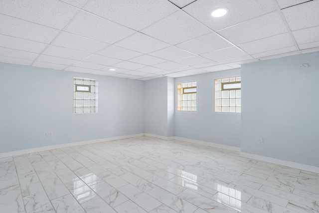 basement featuring a paneled ceiling and plenty of natural light