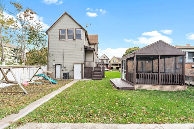 back of property featuring a lawn, a sunroom, and a wooden deck