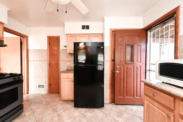 kitchen with tile walls, black appliances, crown molding, and light tile patterned floors