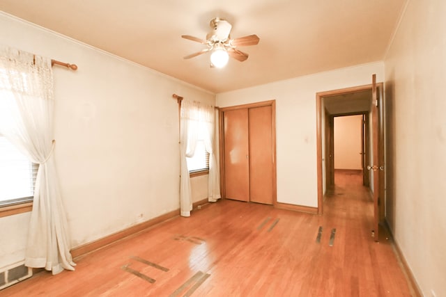 unfurnished bedroom featuring a closet, crown molding, hardwood / wood-style flooring, and ceiling fan