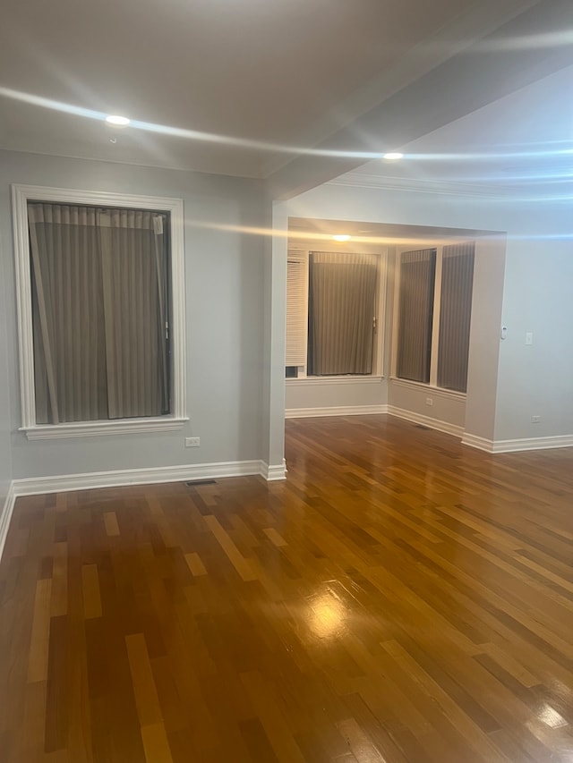 spare room featuring dark wood-type flooring and baseboards