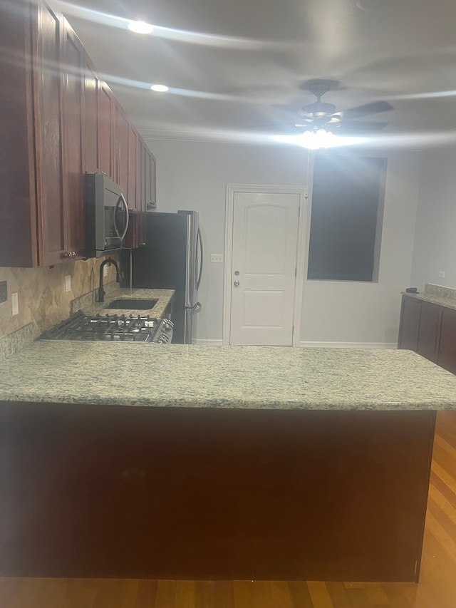 kitchen featuring tasteful backsplash, light countertops, stainless steel microwave, stove, and wood finished floors