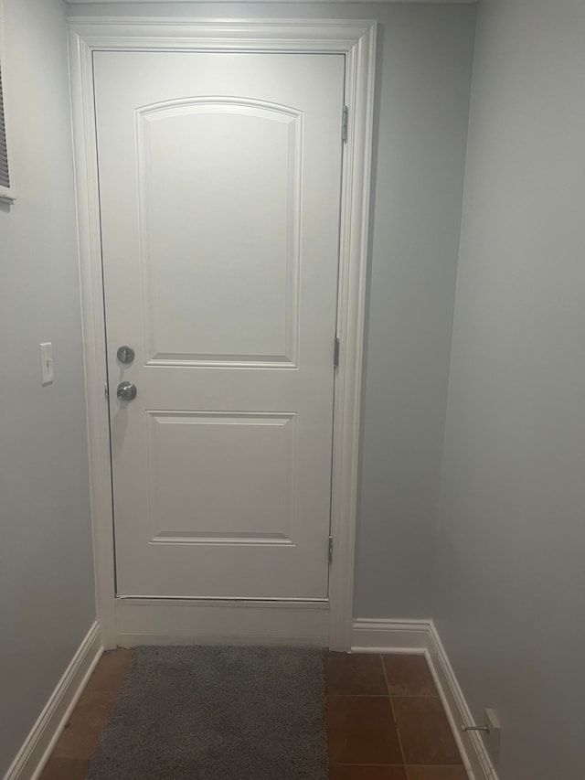 entryway featuring dark tile patterned flooring and baseboards