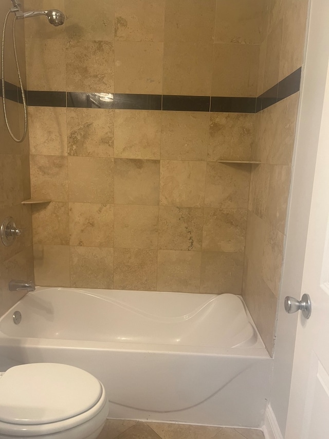 bathroom with tile patterned flooring, toilet, and tiled shower / bath combo