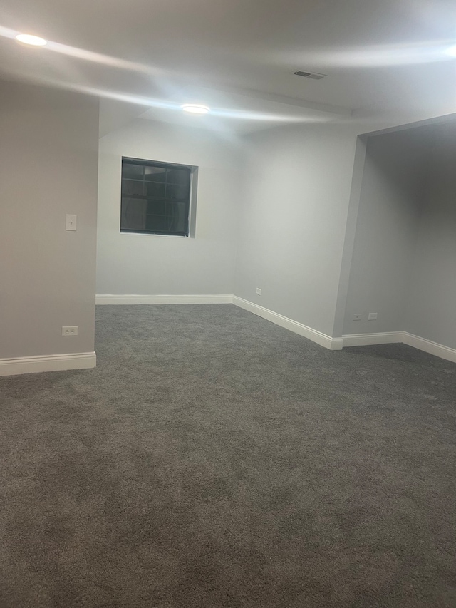 spare room featuring baseboards, visible vents, and dark carpet