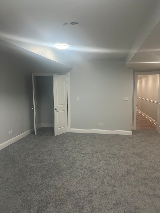 empty room with dark colored carpet, visible vents, and baseboards