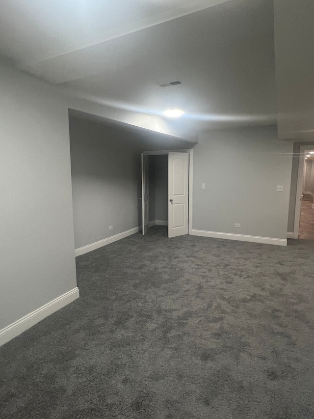 unfurnished room featuring visible vents, dark carpet, and baseboards