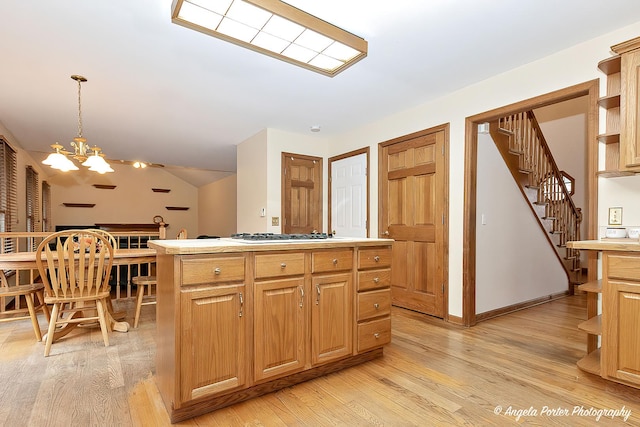 kitchen with white gas stovetop, decorative light fixtures, an inviting chandelier, light hardwood / wood-style flooring, and a kitchen island