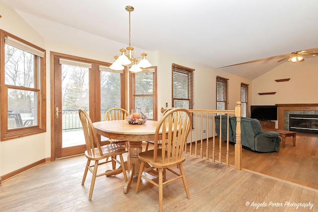 dining room featuring ceiling fan with notable chandelier, light hardwood / wood-style floors, and lofted ceiling