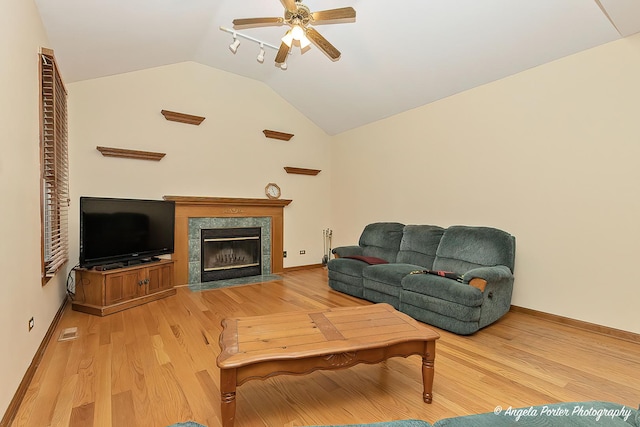 living room featuring a premium fireplace, ceiling fan, light hardwood / wood-style floors, and vaulted ceiling