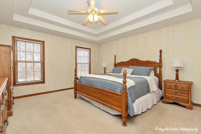 bedroom featuring ceiling fan, a tray ceiling, and multiple windows