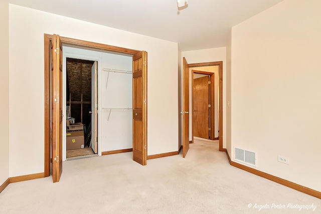 unfurnished bedroom featuring light carpet and a closet