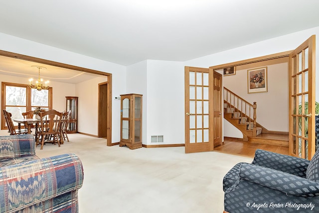 living room featuring carpet flooring, french doors, and a notable chandelier