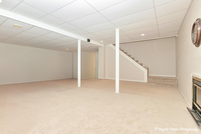 basement featuring light carpet and a drop ceiling