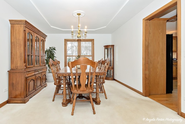 carpeted dining area with a raised ceiling and a notable chandelier