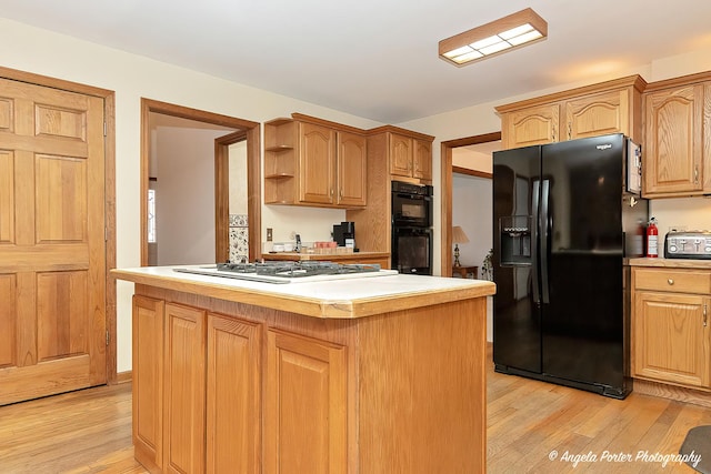 kitchen featuring black appliances, a kitchen island, and light wood-type flooring