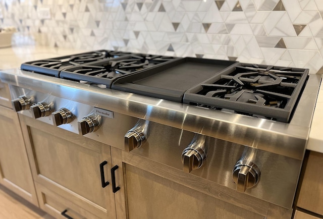 details featuring backsplash and stainless steel gas cooktop