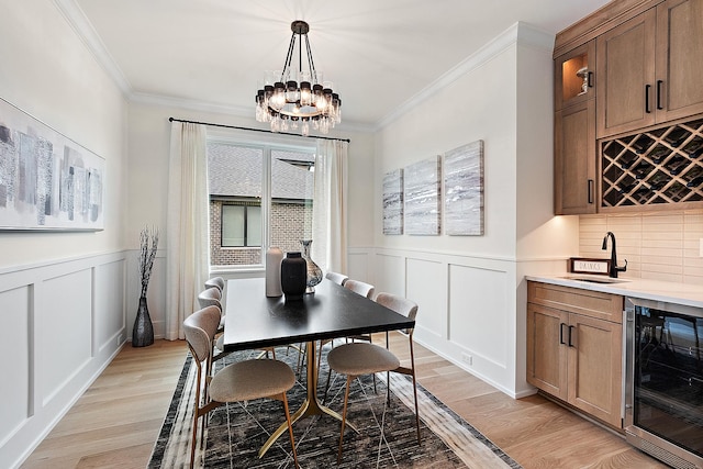 dining space featuring wine cooler, wet bar, a chandelier, and light wood-type flooring