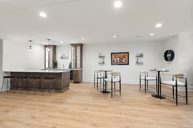 kitchen featuring pendant lighting, a breakfast bar, sink, light hardwood / wood-style floors, and kitchen peninsula