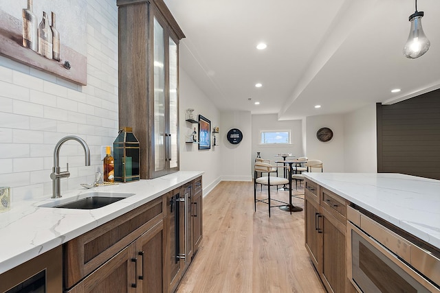 11060 Lizmore Ln Unit 27B, Orland Park, IL 60467 - kitchen with a sink, stainless steel microwave, tasteful backsplash, light wood-style flooring, and light stone countertops