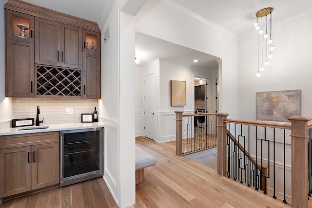11060 Lizmore Ln Unit 27B, Orland Park, IL 60467 - indoor wet bar with beverage cooler, crown molding, backsplash, light wood finished floors, and pendant lighting