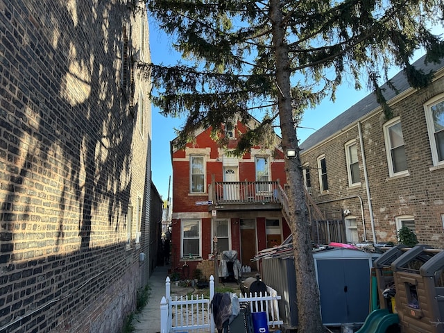 view of front of property featuring a balcony and a storage shed