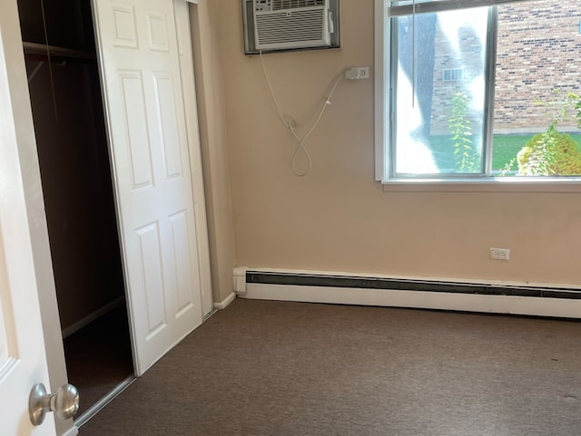 unfurnished bedroom with dark carpet, baseboard heating, a closet, and a wall unit AC