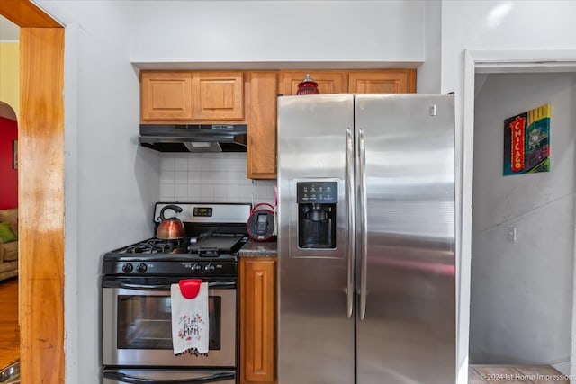 kitchen featuring appliances with stainless steel finishes, decorative backsplash, and dark stone countertops