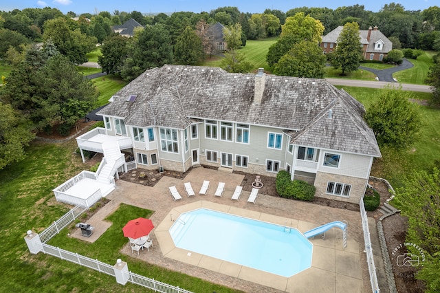 rear view of house with a fenced in pool and a patio